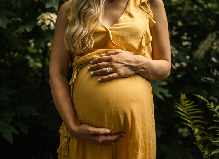 Maternity portrait of a pregnant lady wearing a yellow dress in a wicker  peacock chair