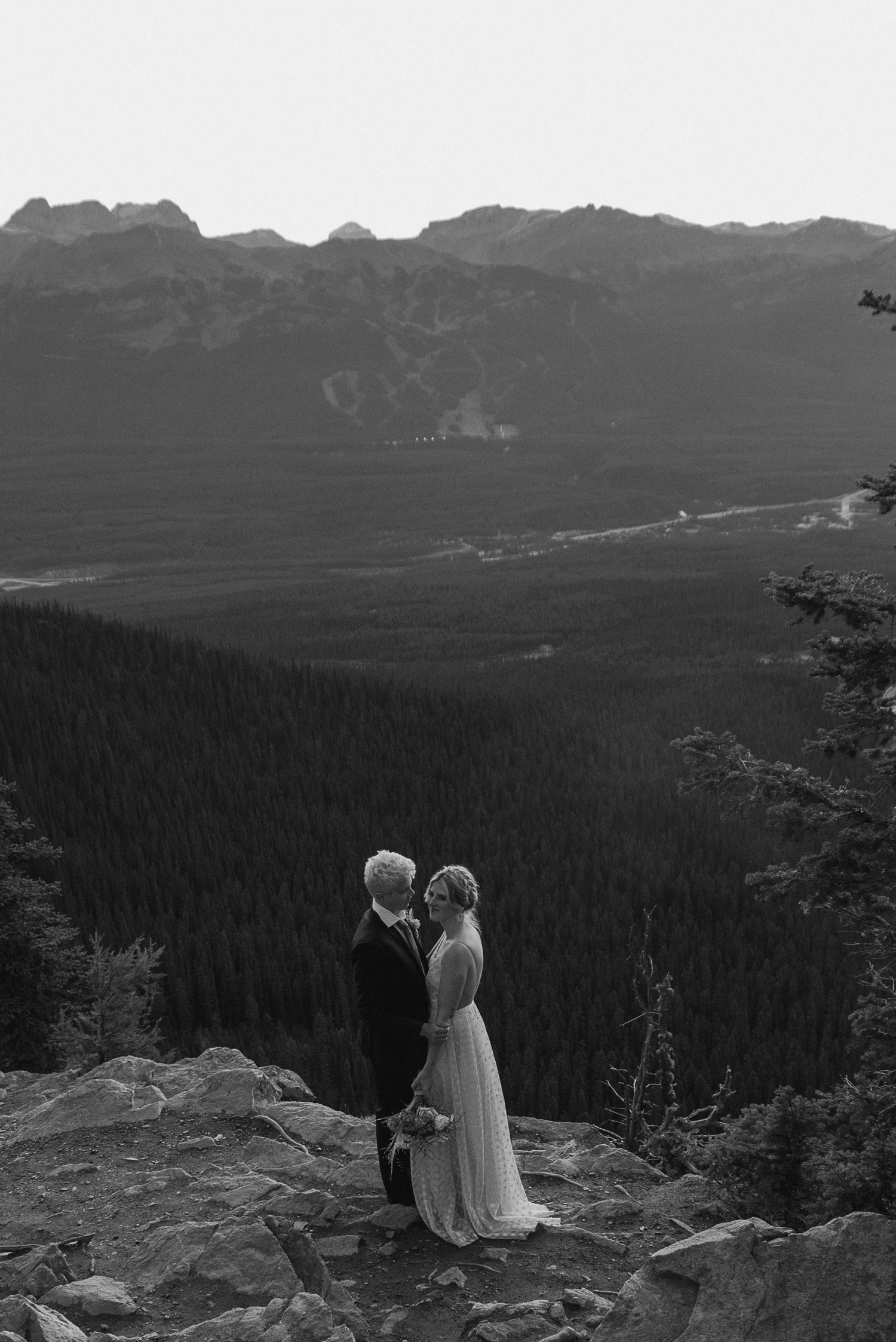 black and white shot of couple embracing and kissing just before the sun rises above the mountain ridge during a hiking style elopement
