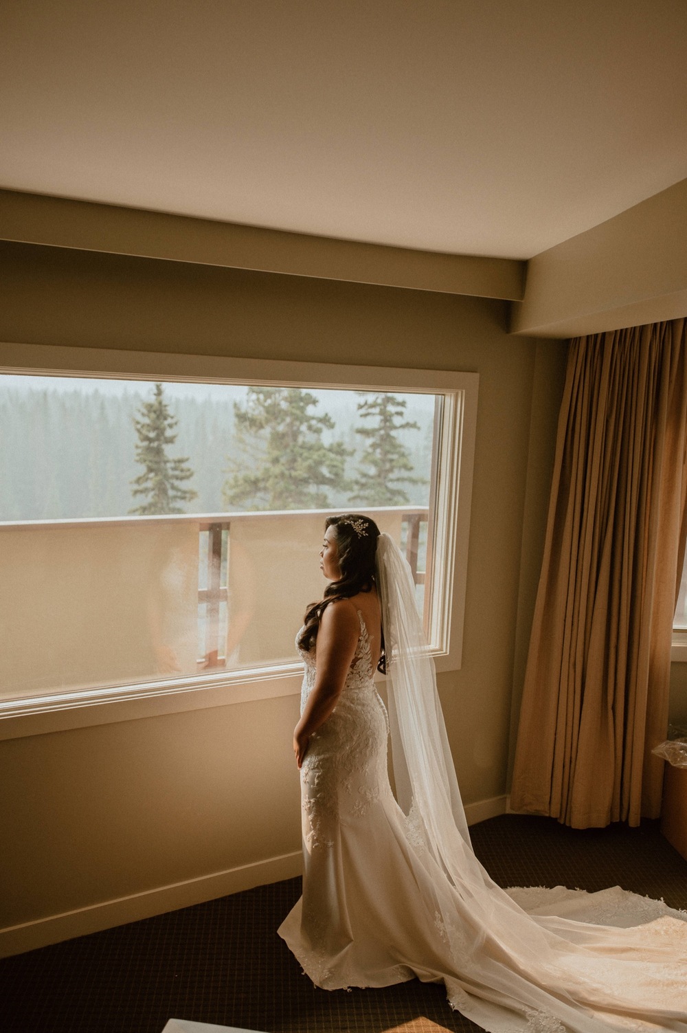bride posing in front of window for a mountain elopement during wildfire season in Banff Alberta