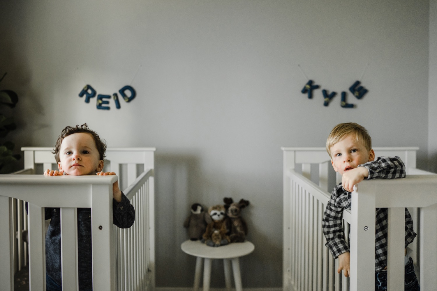 Twin boys in cribs looking at camera during in-home family session