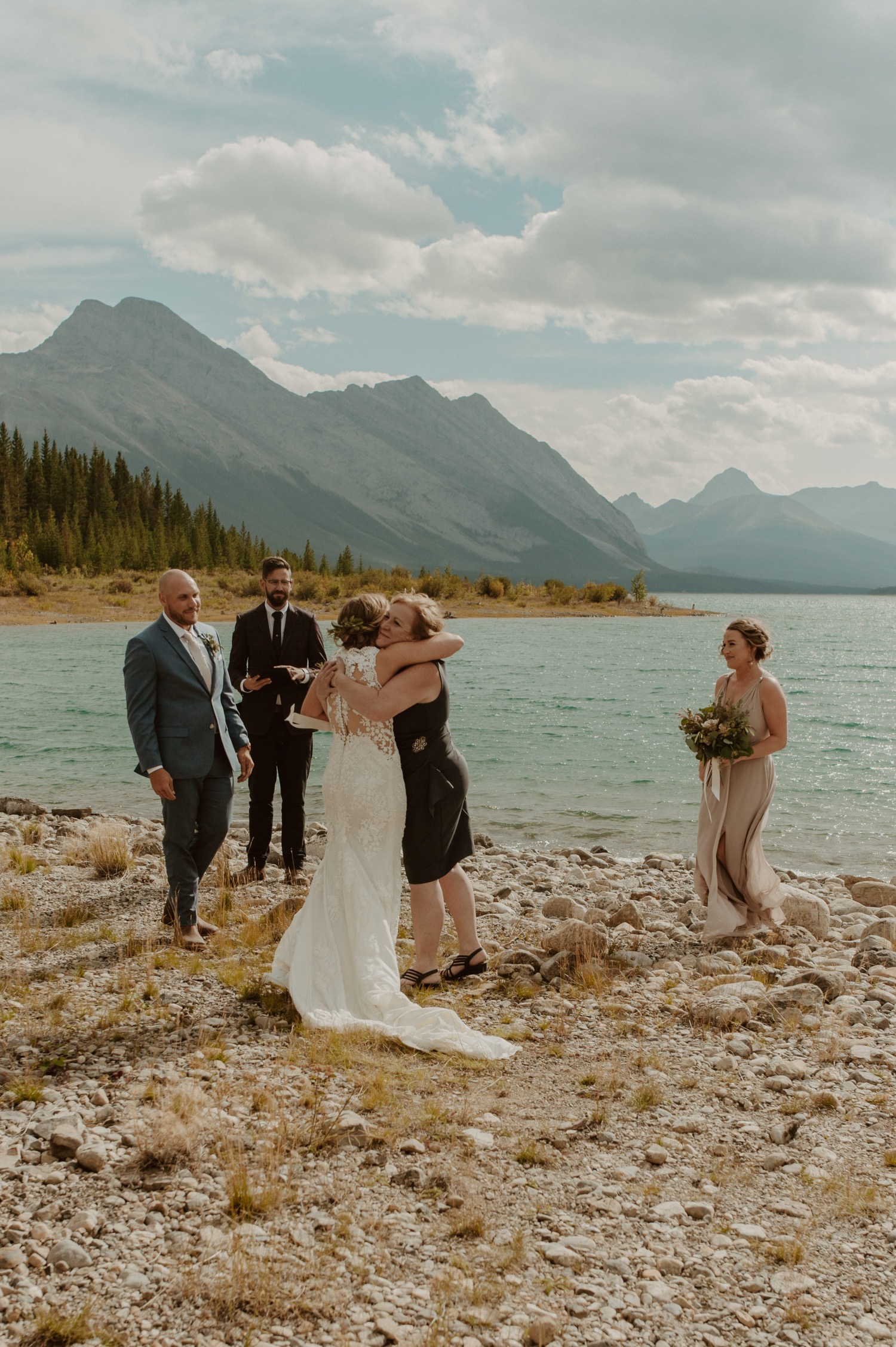The mother walks the bride down the make shift aisle for their ceremony on the shore of Spray Lakes Alberta
