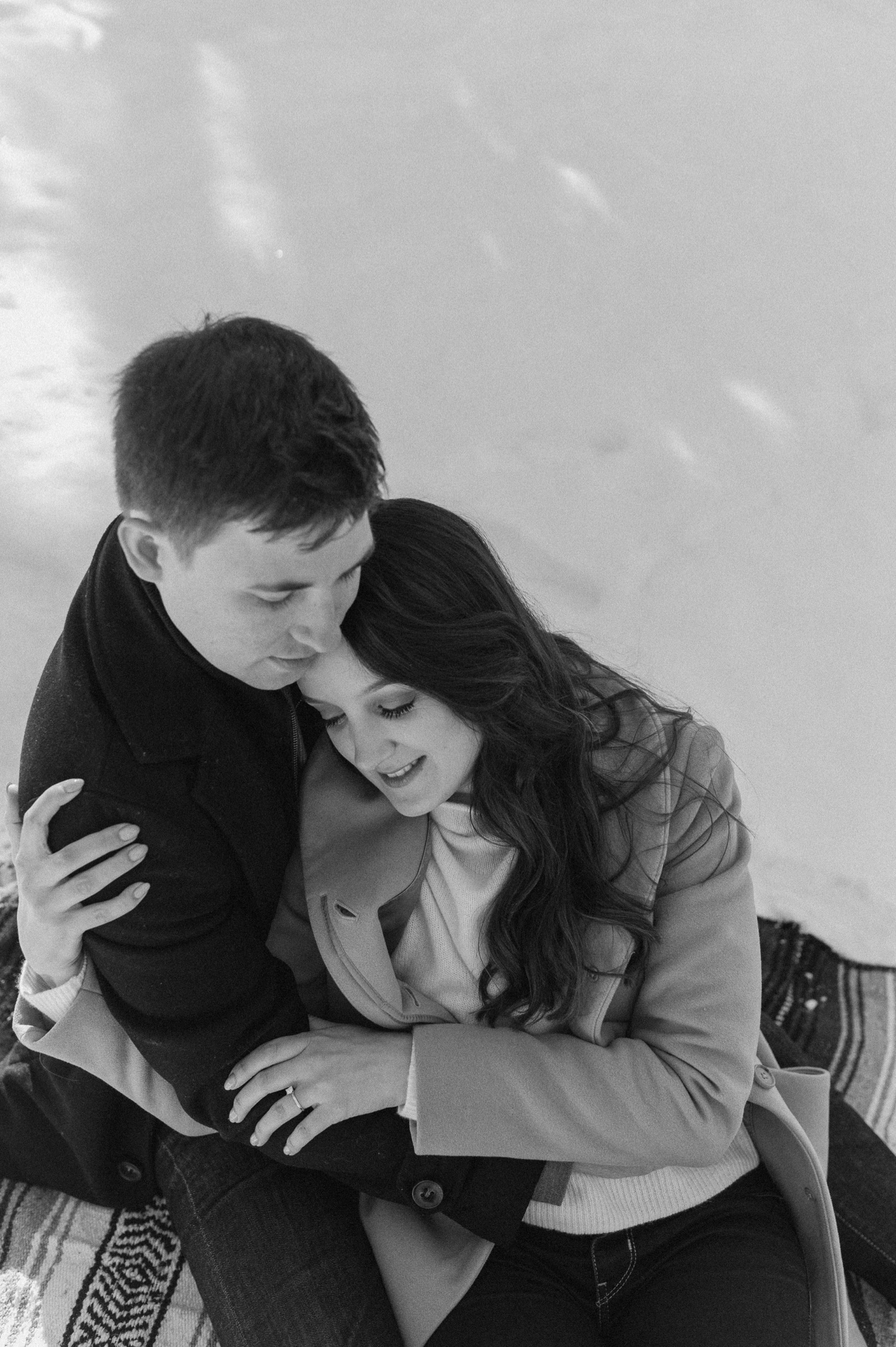 black and white shot of couple cuddling in the snow during a picnic for an engagement session in the Rocky Mountains of Alberta