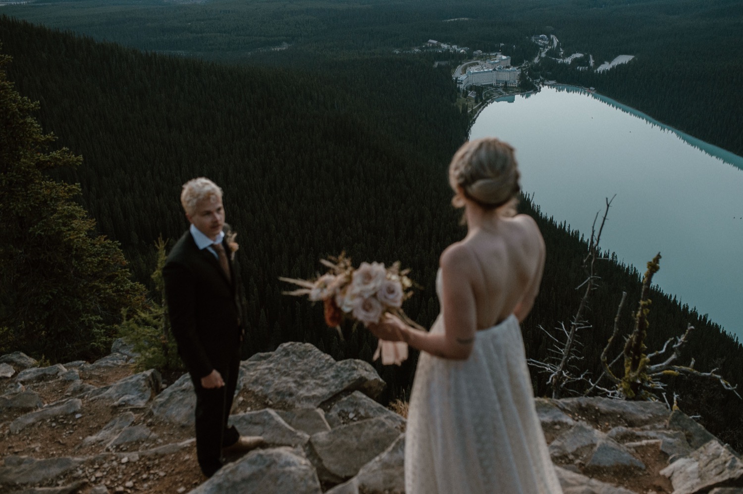 groom seeing his bride for the first time on top of the mountain before a hiking styled elopement in Lake Louise Alberta