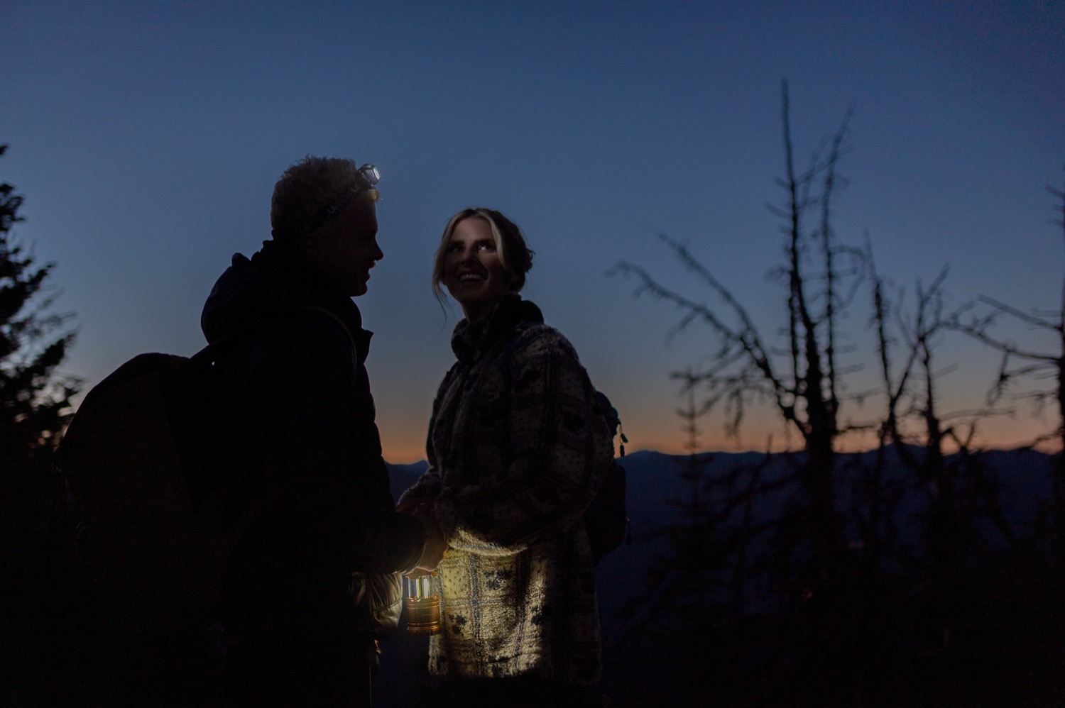couple meeting before sunrise by headlamp light  at the top of the mountain before a hiking elopement styled shoot in Alberta Canada