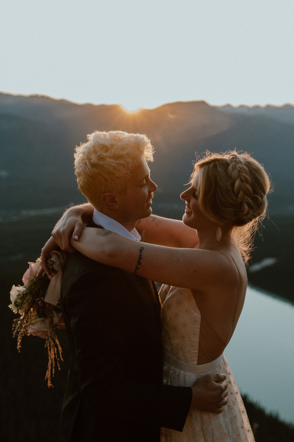 couple embracing and kissing just as the sun rises above the mountain ridge during a hiking style elopement