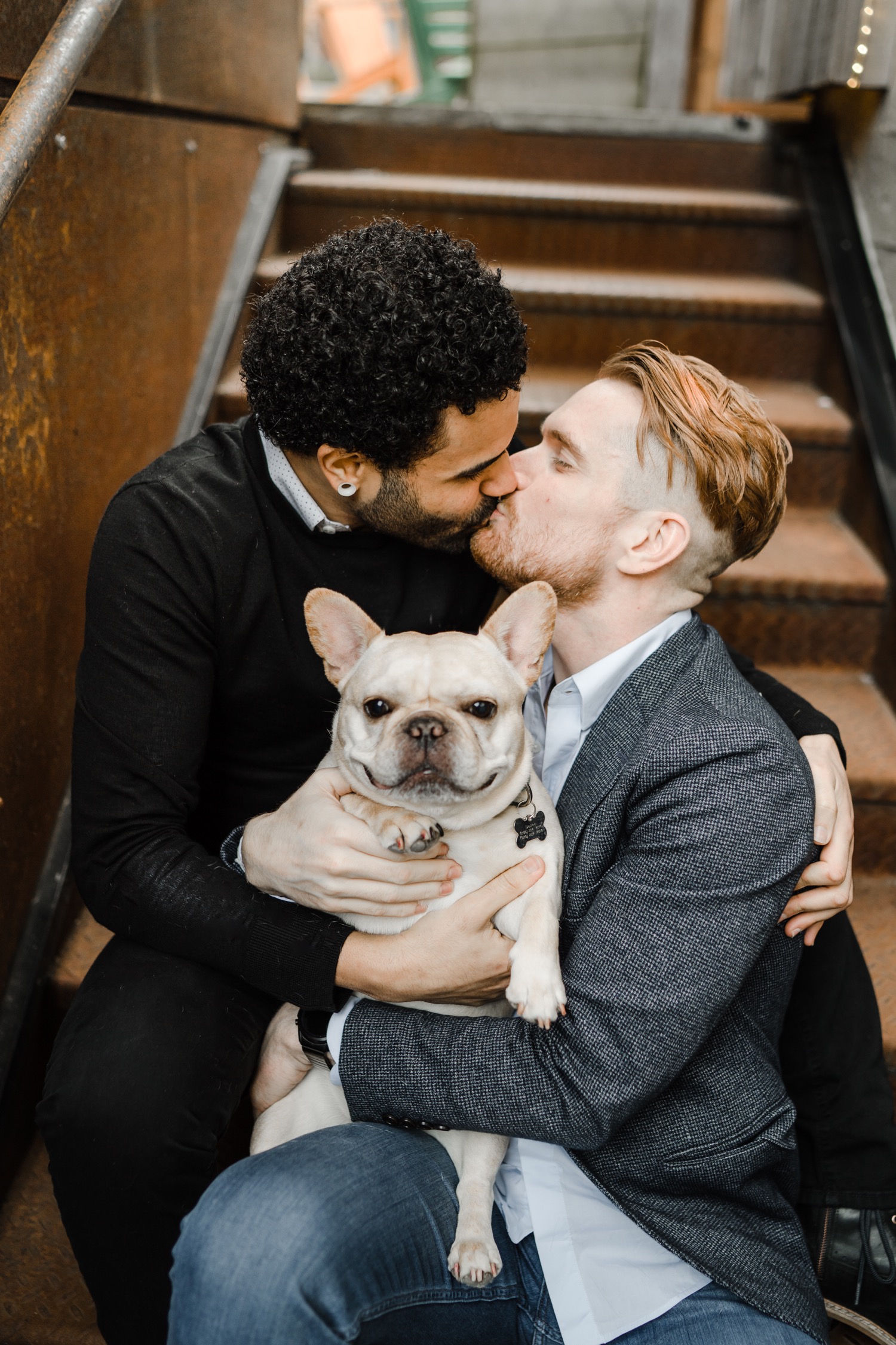 Couple kissing while Frenchie dog looks at the camera during couples session