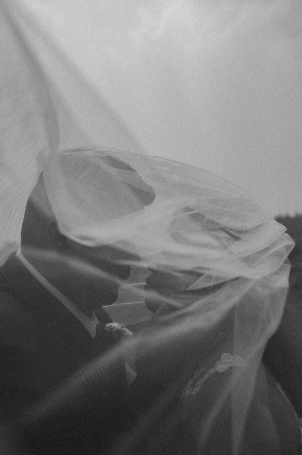 black and white artistic shot of bride and groom under veil for a mountain elopement during wildfire season in Banff Alberta