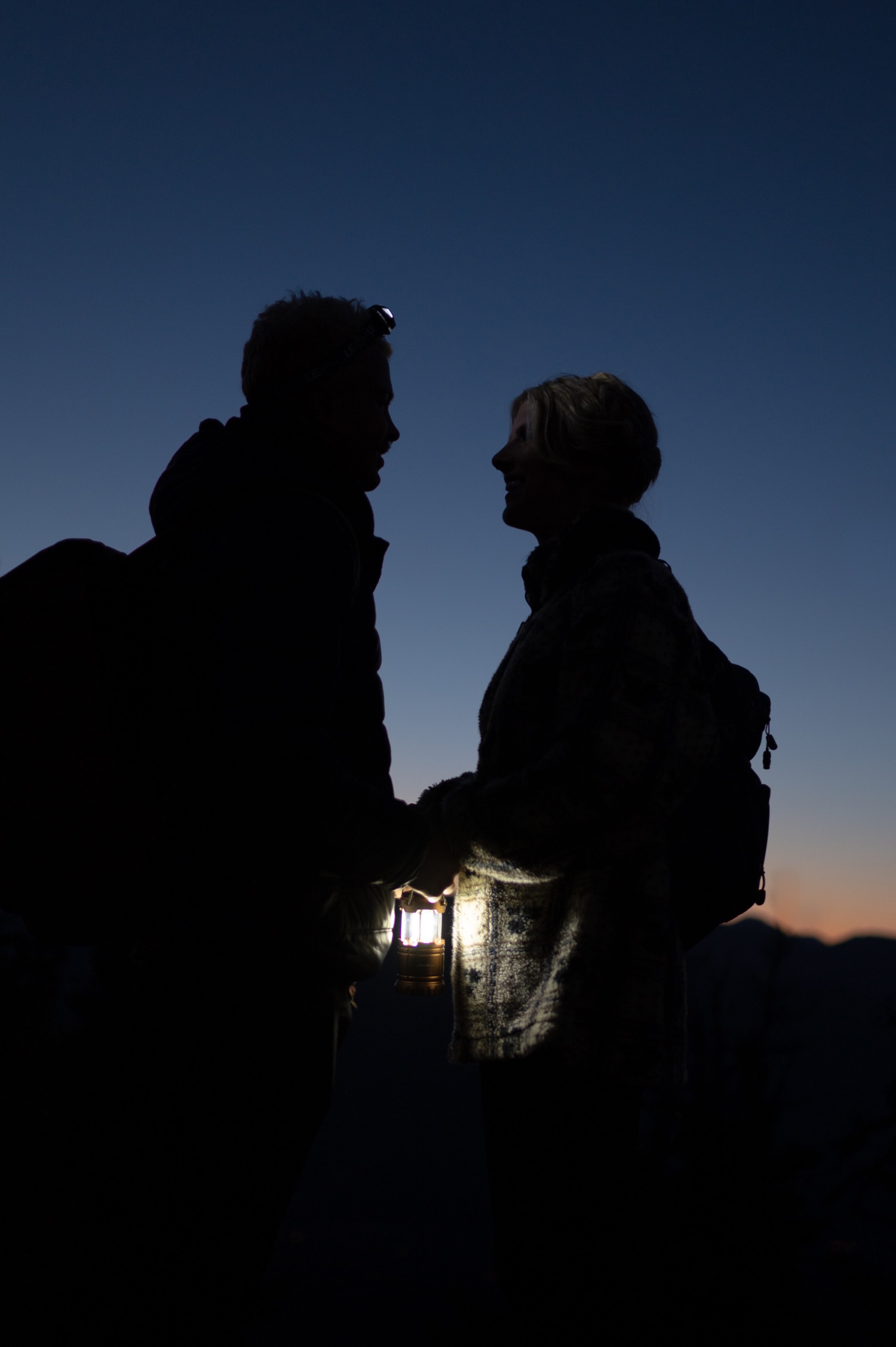 couple meeting before sunrise by headlamp light  at the top of the mountain before a hiking elopement styled shoot in Alberta Canada