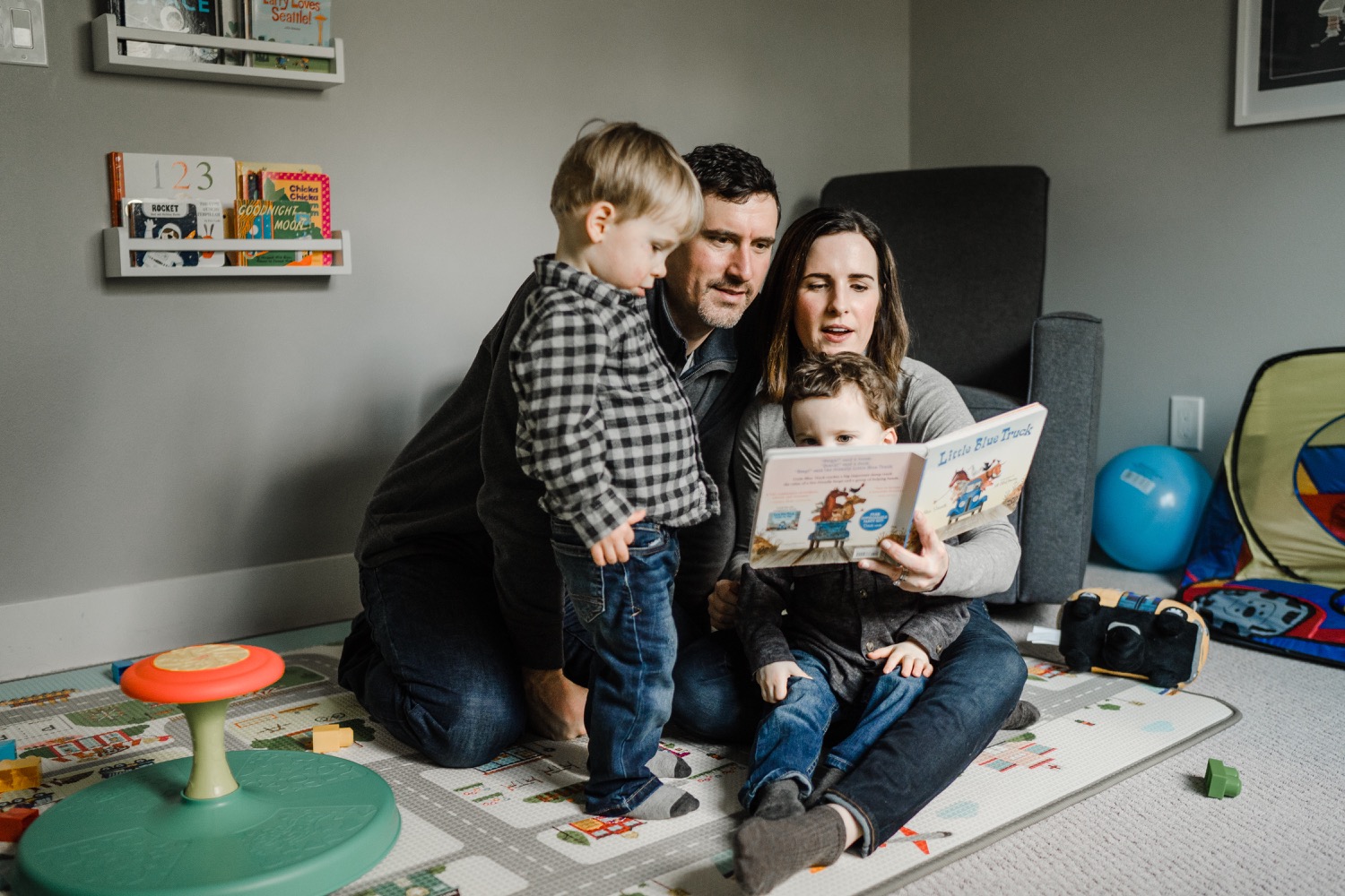 Family reading book together in playroom during in-home family session