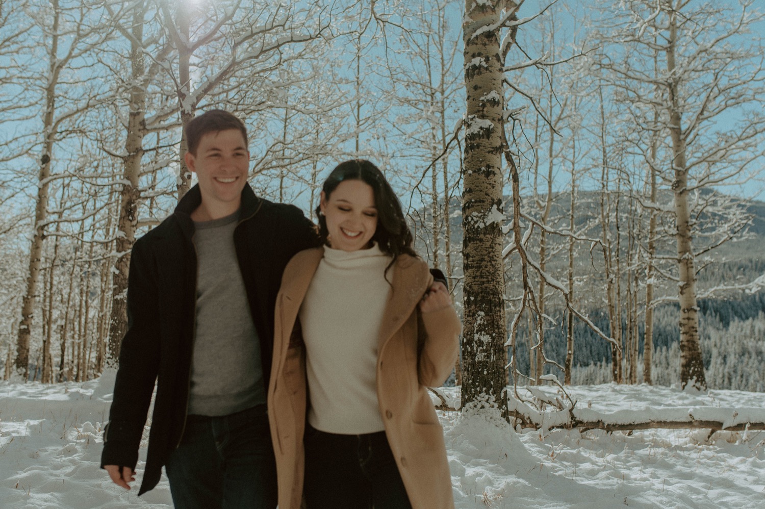 couple walking through a forest together during a winter engagement session in the rocky mountains of alberta
