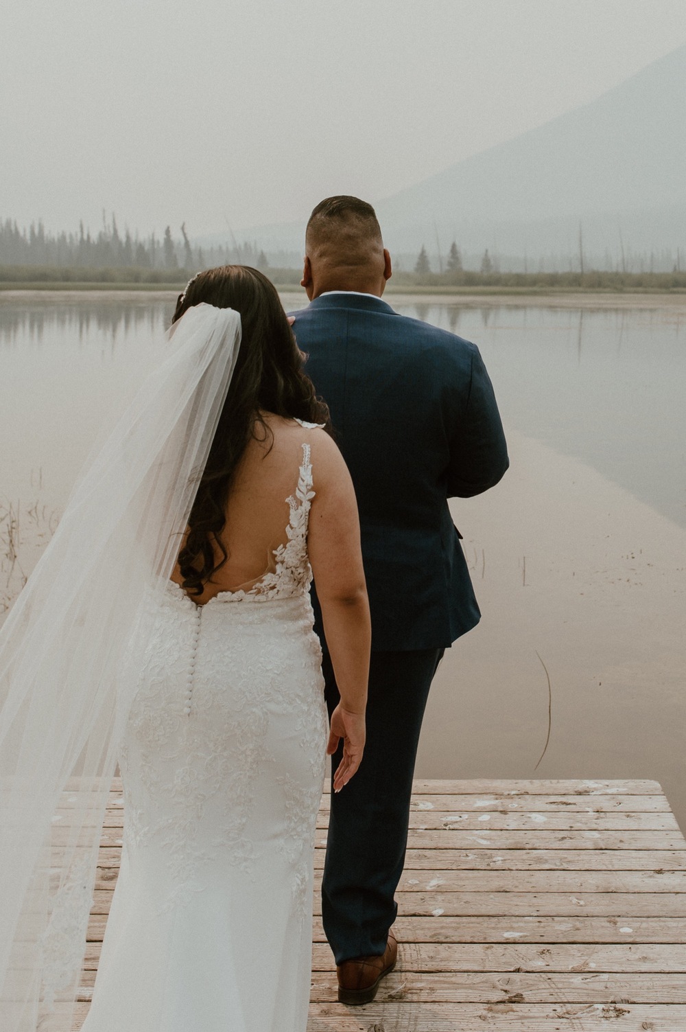 bride behind groom waiting to do first look for a mountain elopement during wildfire season in Banff Alberta