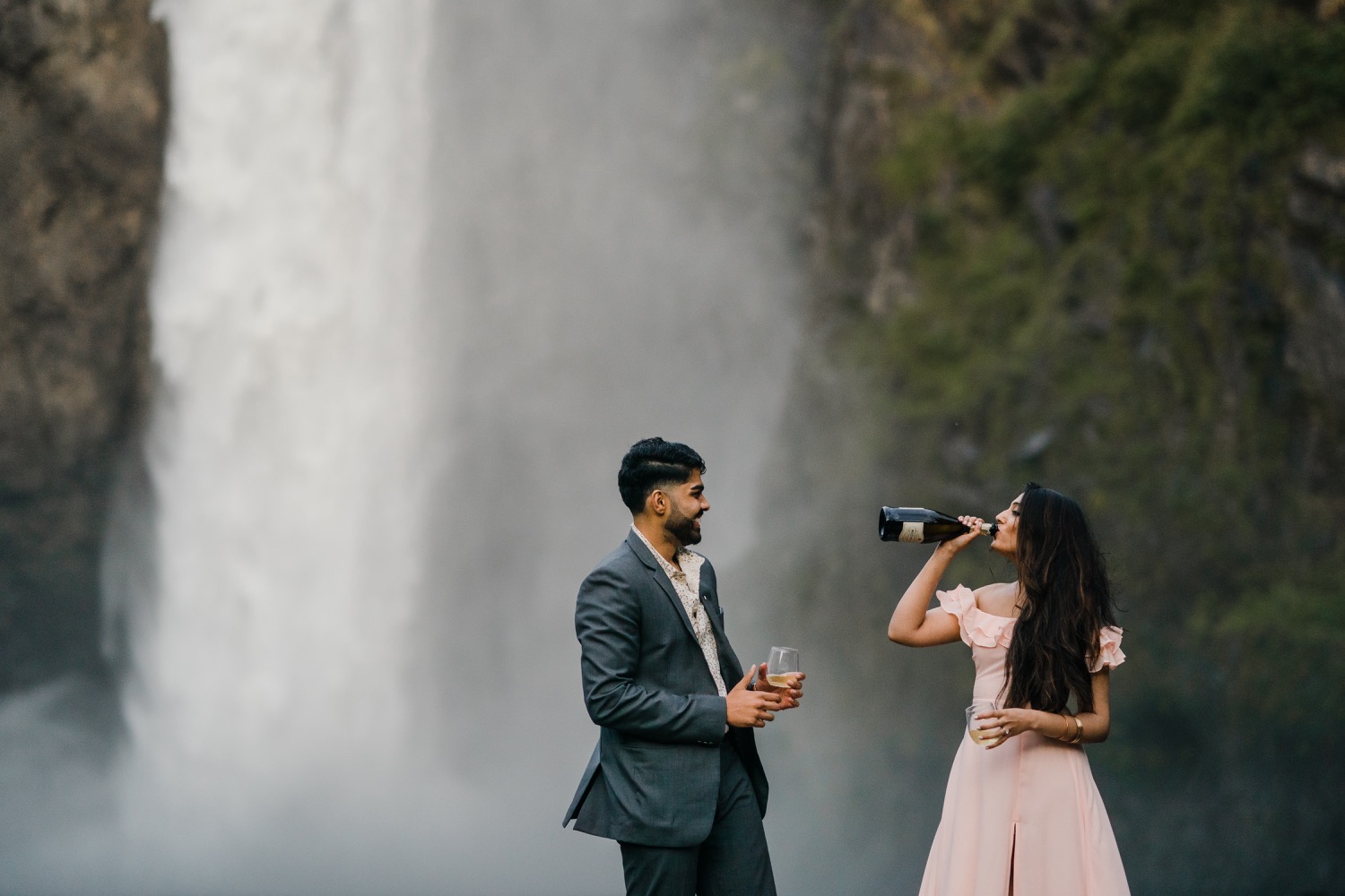 Woman drinks from the champagne bottle at Snoqualmie Falls