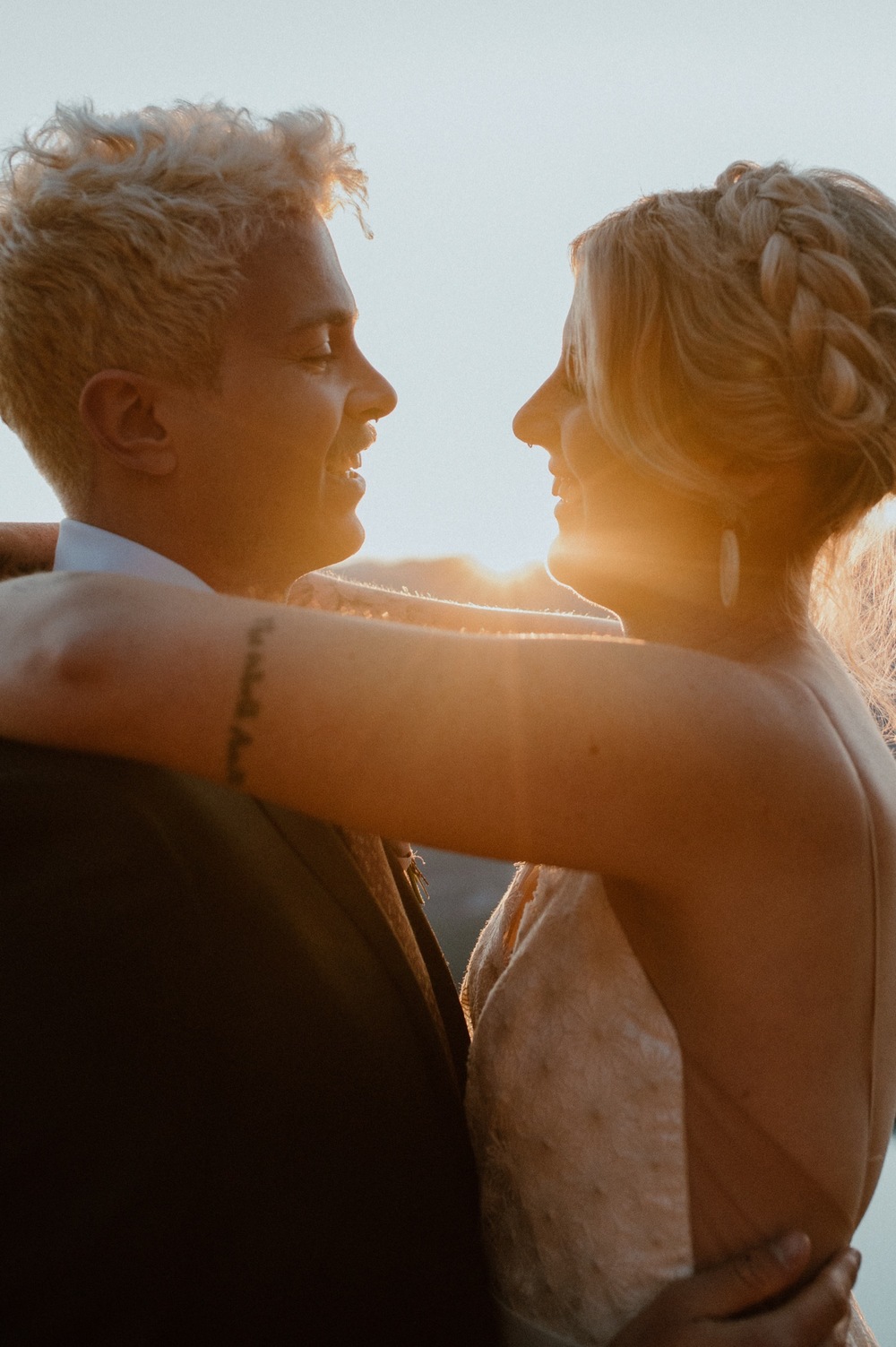 couple embracing and kissing just as the sun rises above the mountain ridge during a hiking style elopement