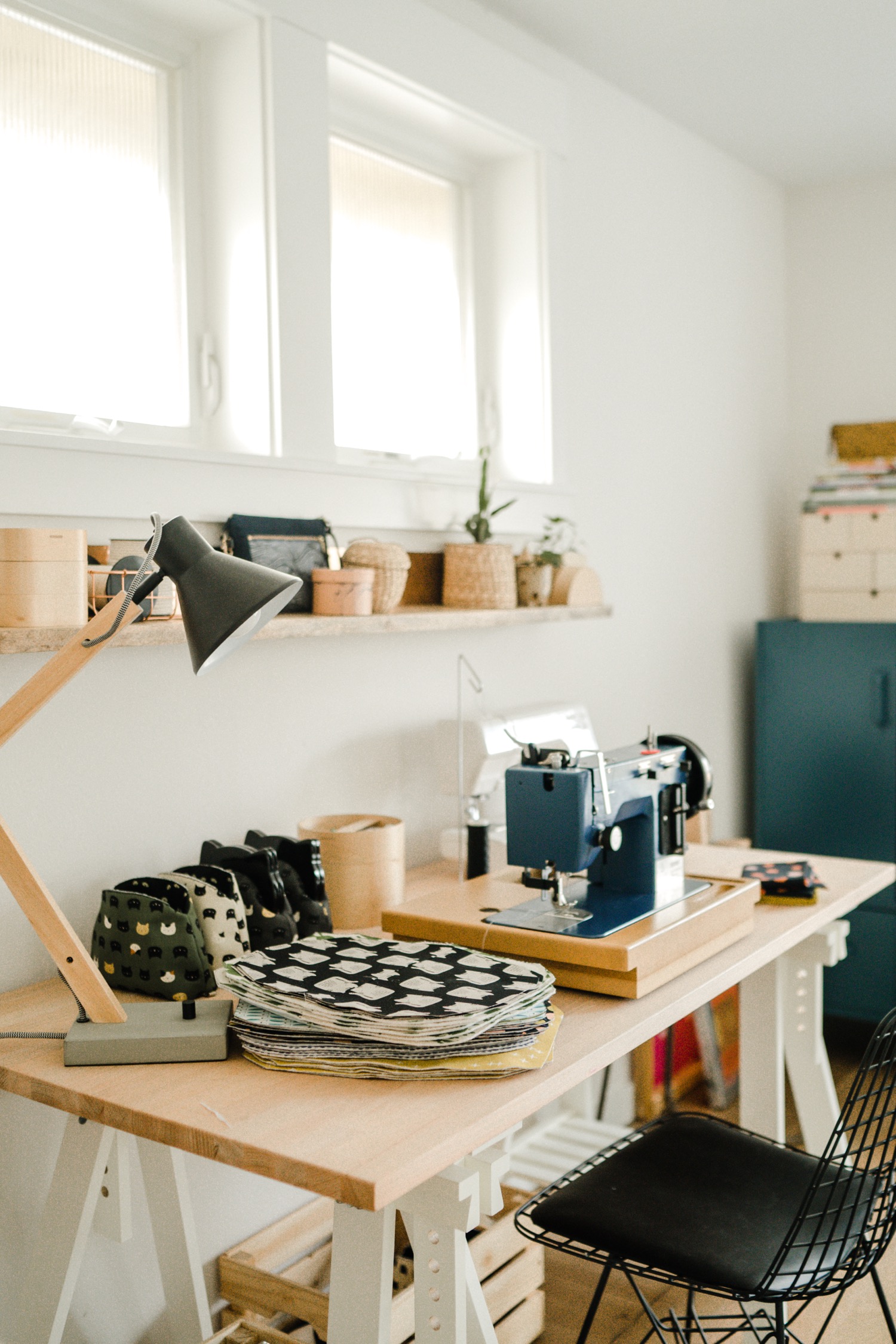Work desk with blue sewing machine and lamp with a stack of fabrick