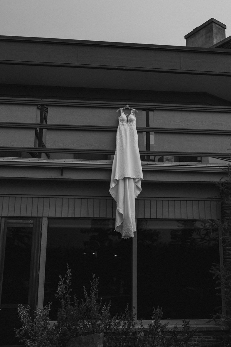 black and white shot of dress hanging from balcony at juniper hotel for a mountain elopement during wildfire season in Banff Alberta