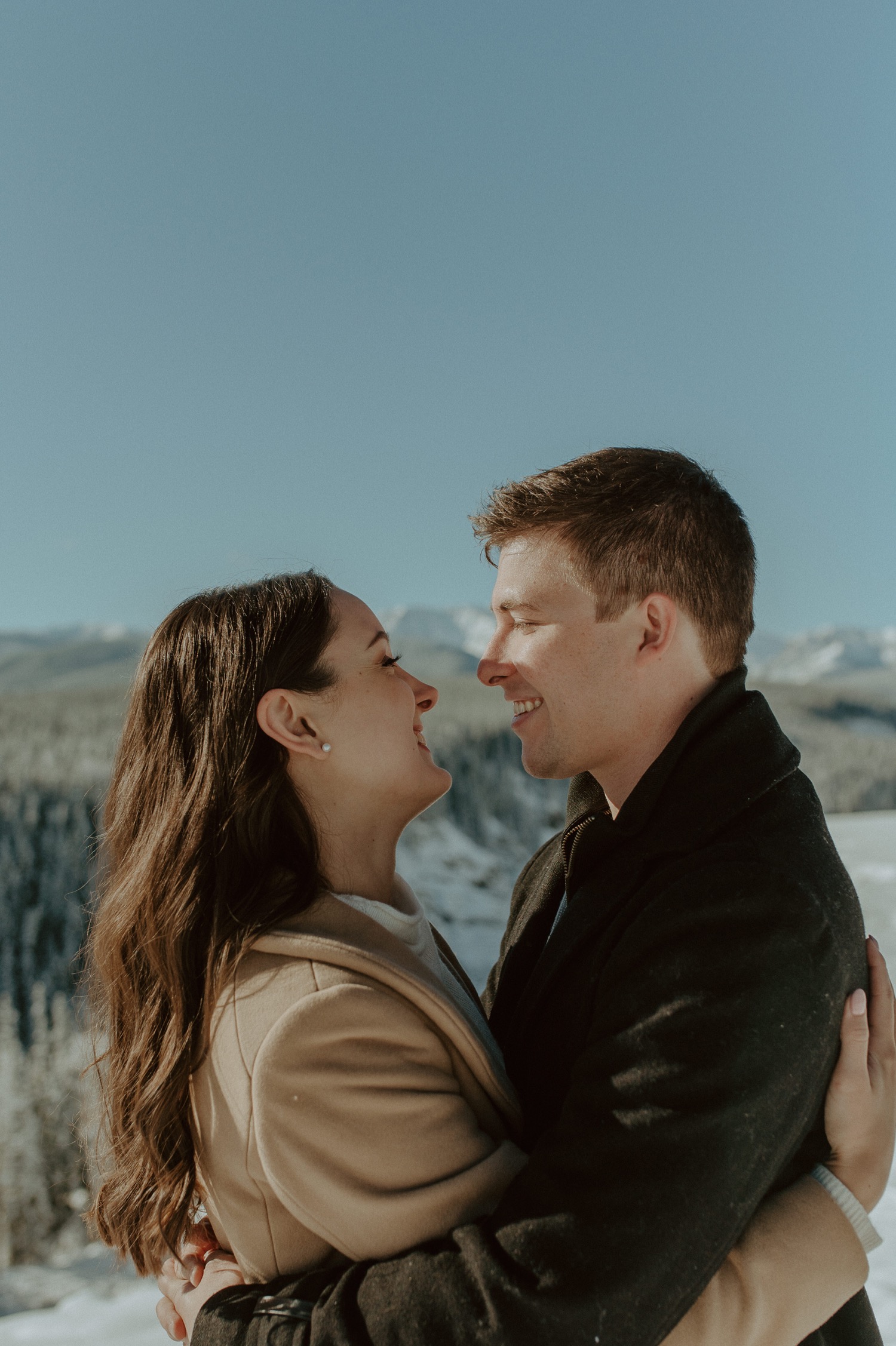 couple looking lovingly at each other during a winter engagement session in the rocky mountains of Alberta