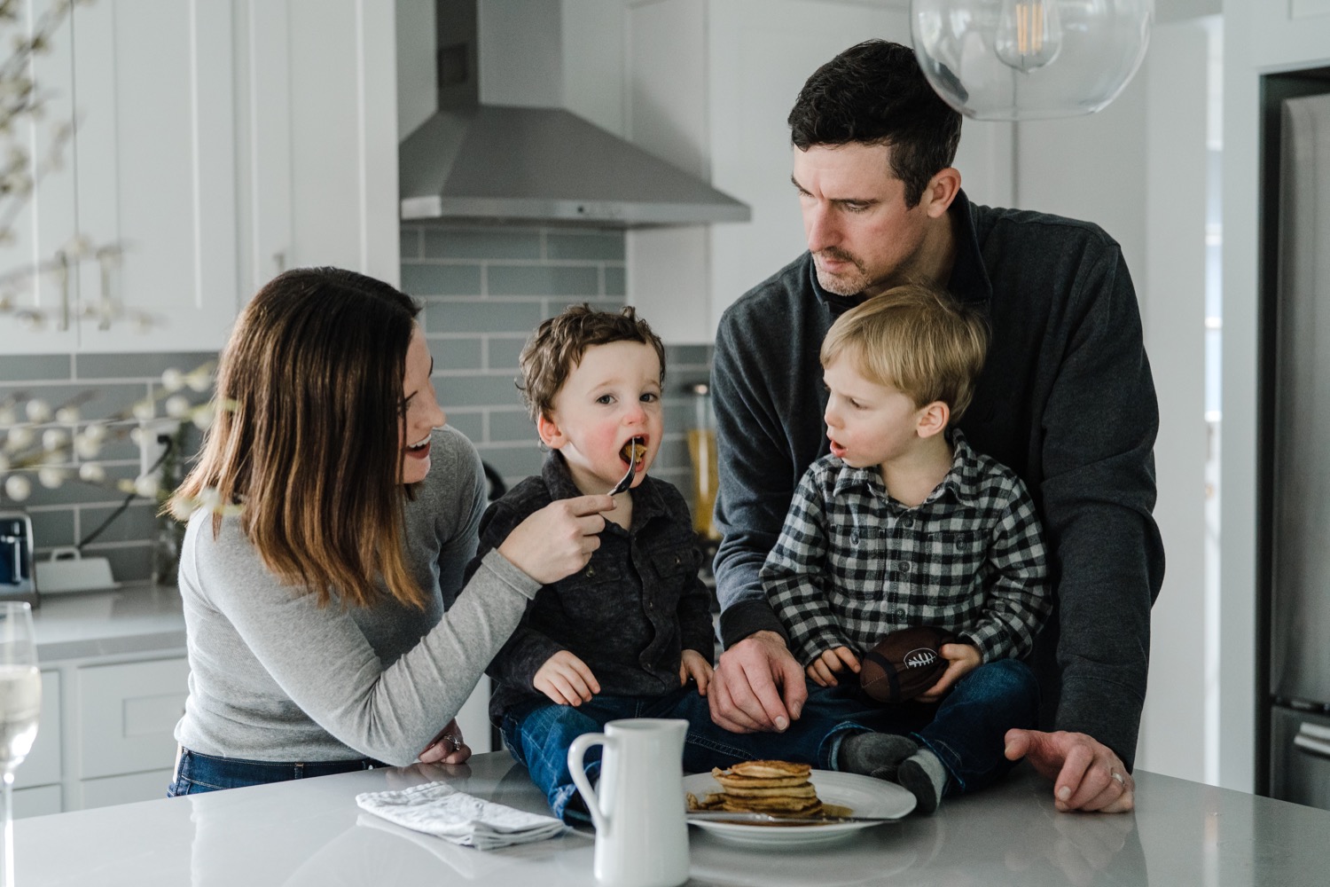 Mother feeding little boy bite of pancakes during in-home family session
