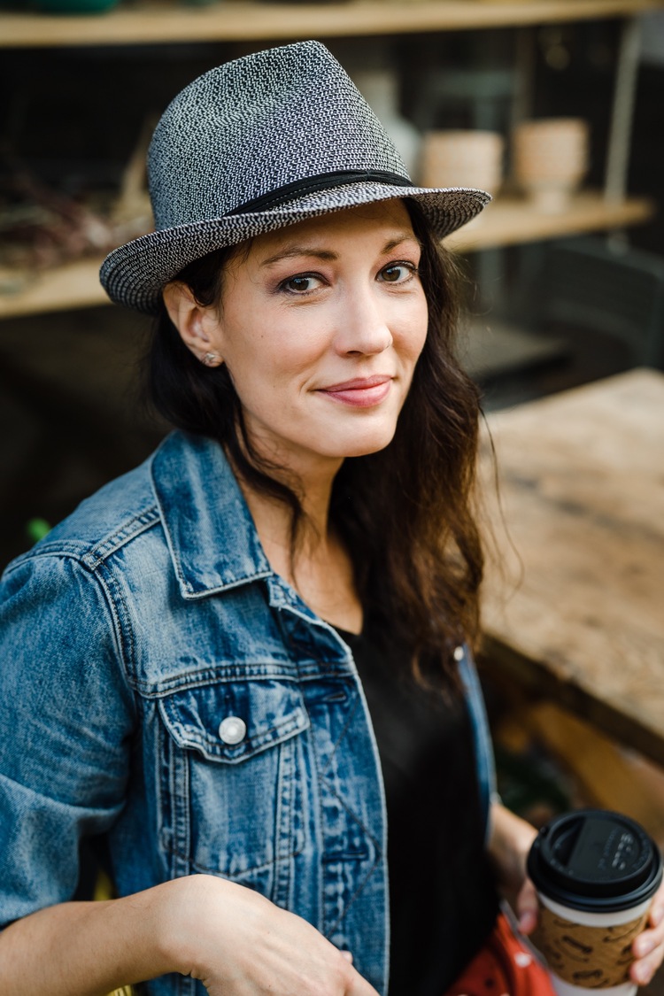 Woman smiling at the camera while wearing denim jacket and fedora for Pioneer Square portrait session.