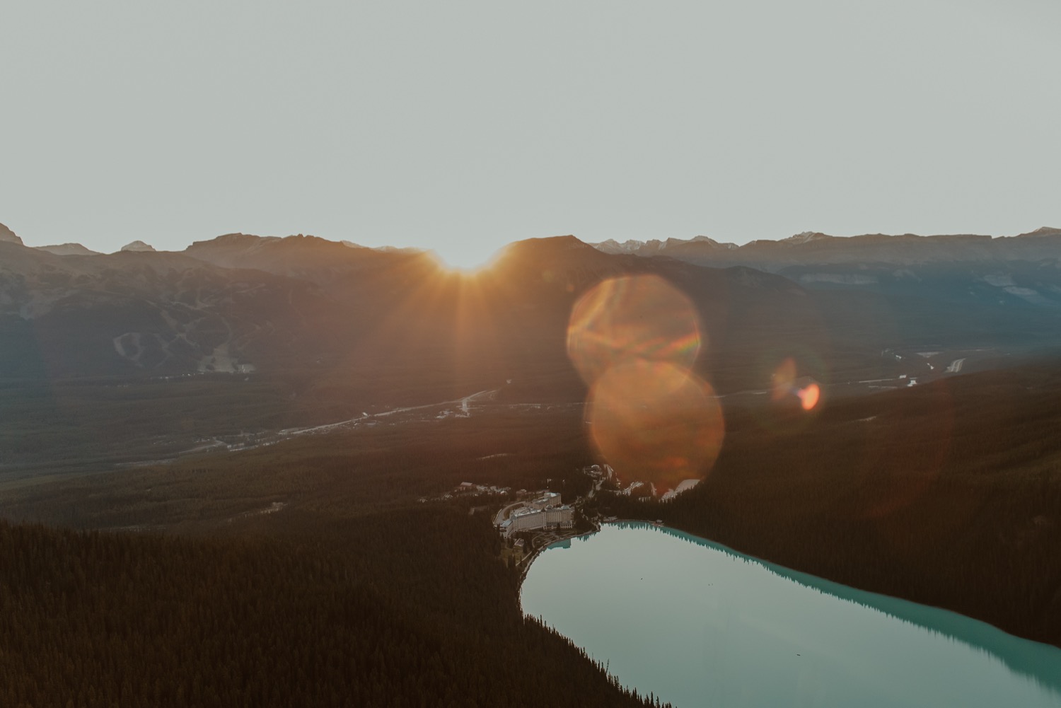 landscape shot of sun rising over mountain ridge in front of Lake Louise Alberta
