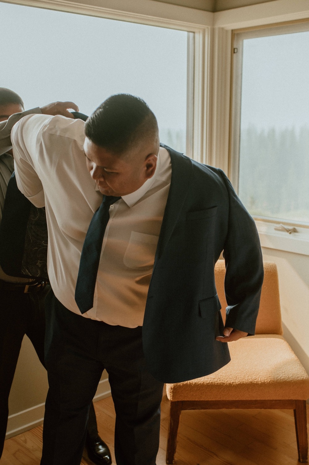 groom putting on jacket for a mountain elopement during wildfire season in Banff Alberta