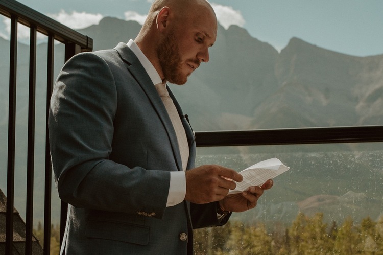 The groom going over his vows for his elopement at their mountain airbnb in Canmore AB