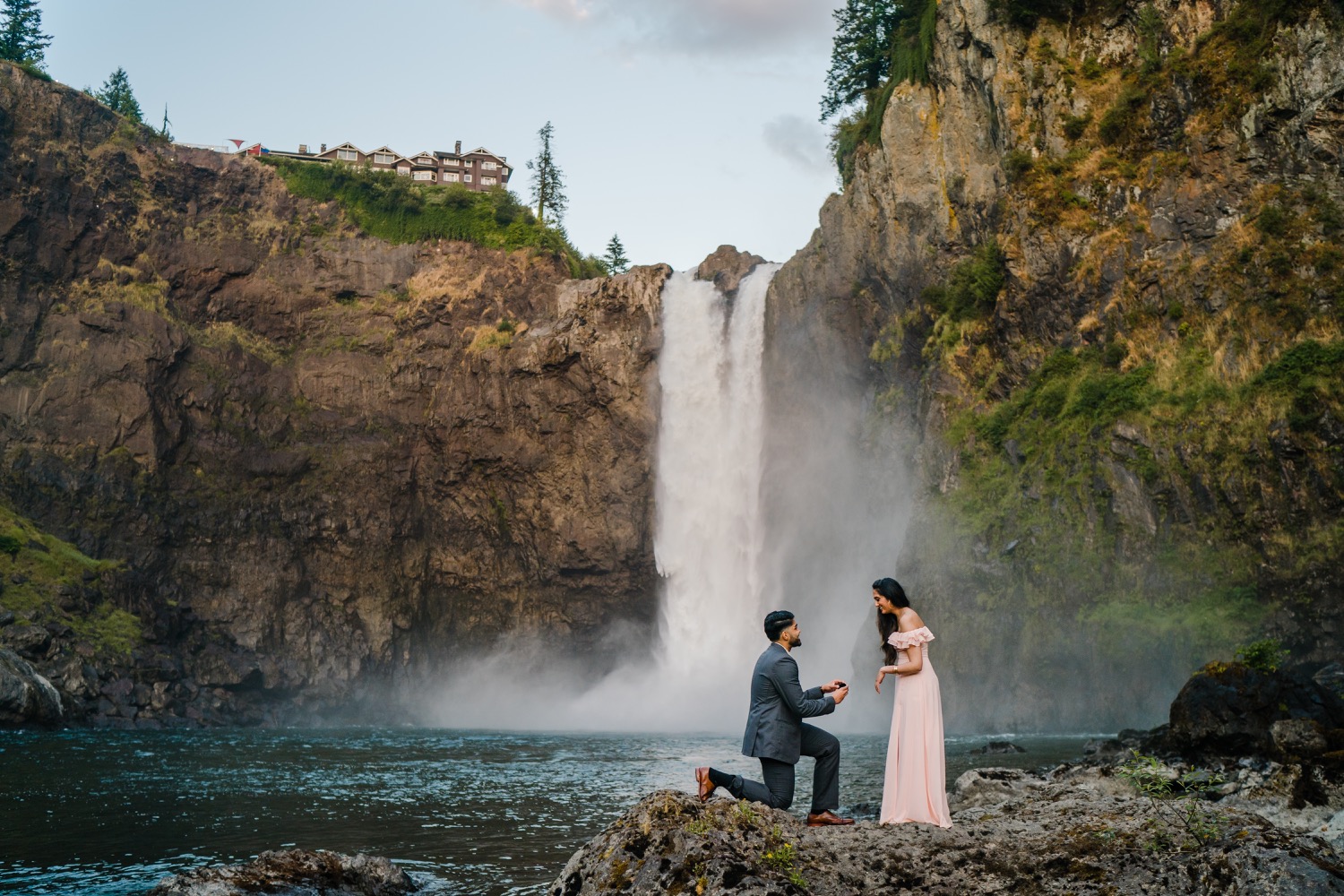 Man kneels down for surprise proposal with Snoqualmie Falls in the background
