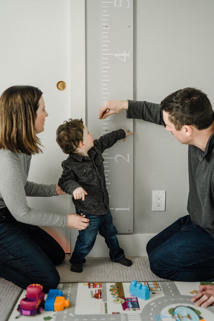 Parents measuring height of little boy