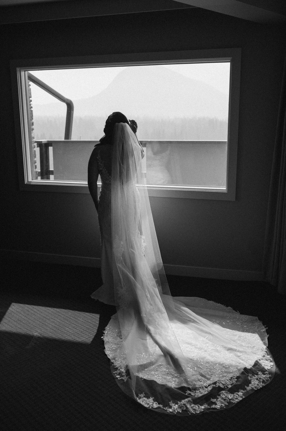 black and white shot of bride standing in front of window for a mountain elopement during wildfire season in Banff Alberta
