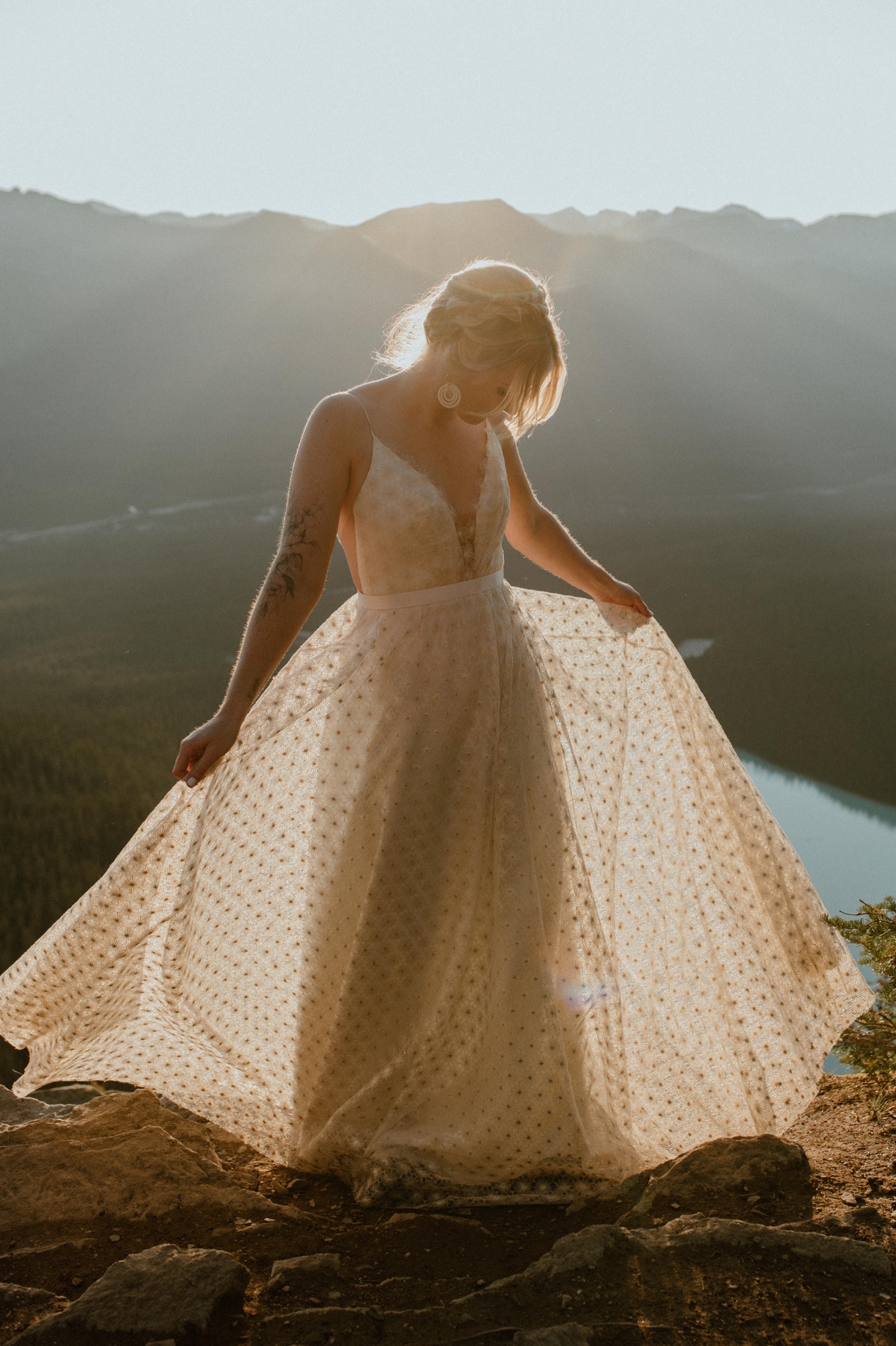 bride portrait shot of her spinning her dress in the morning light from the top fo a mountain during a hiking styled elopement in Alberta