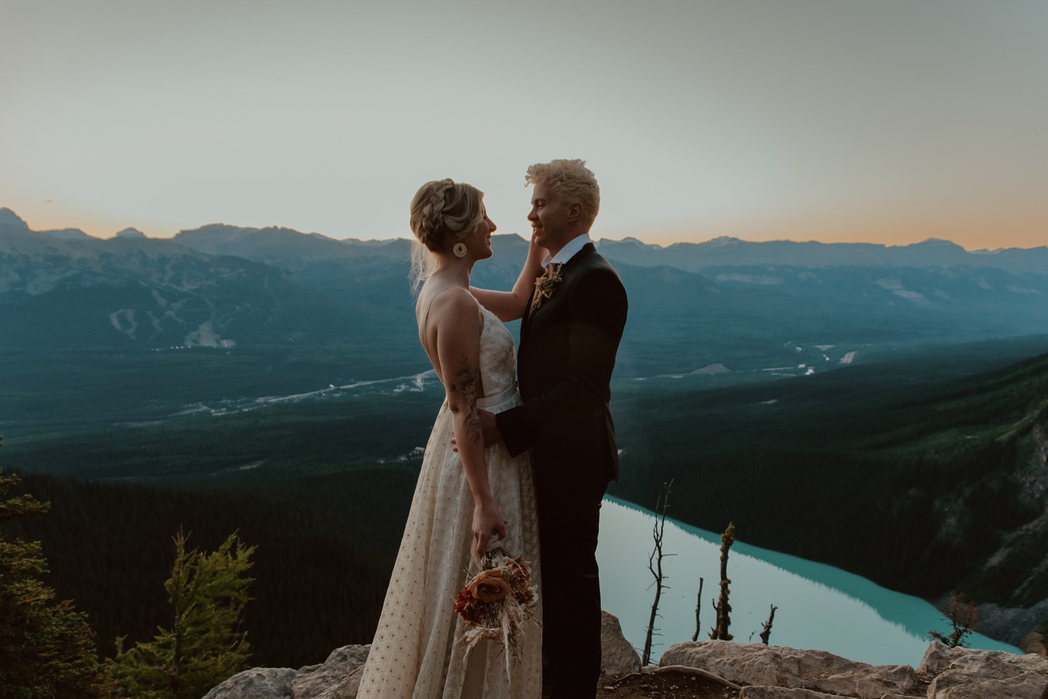 couple embracing and kissing just before the sun rises above the mountain ridge during a hiking style elopement