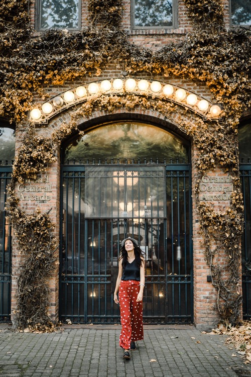 Woman walking towards the camera in front of an iron arched door during Pioneer Square portraits.